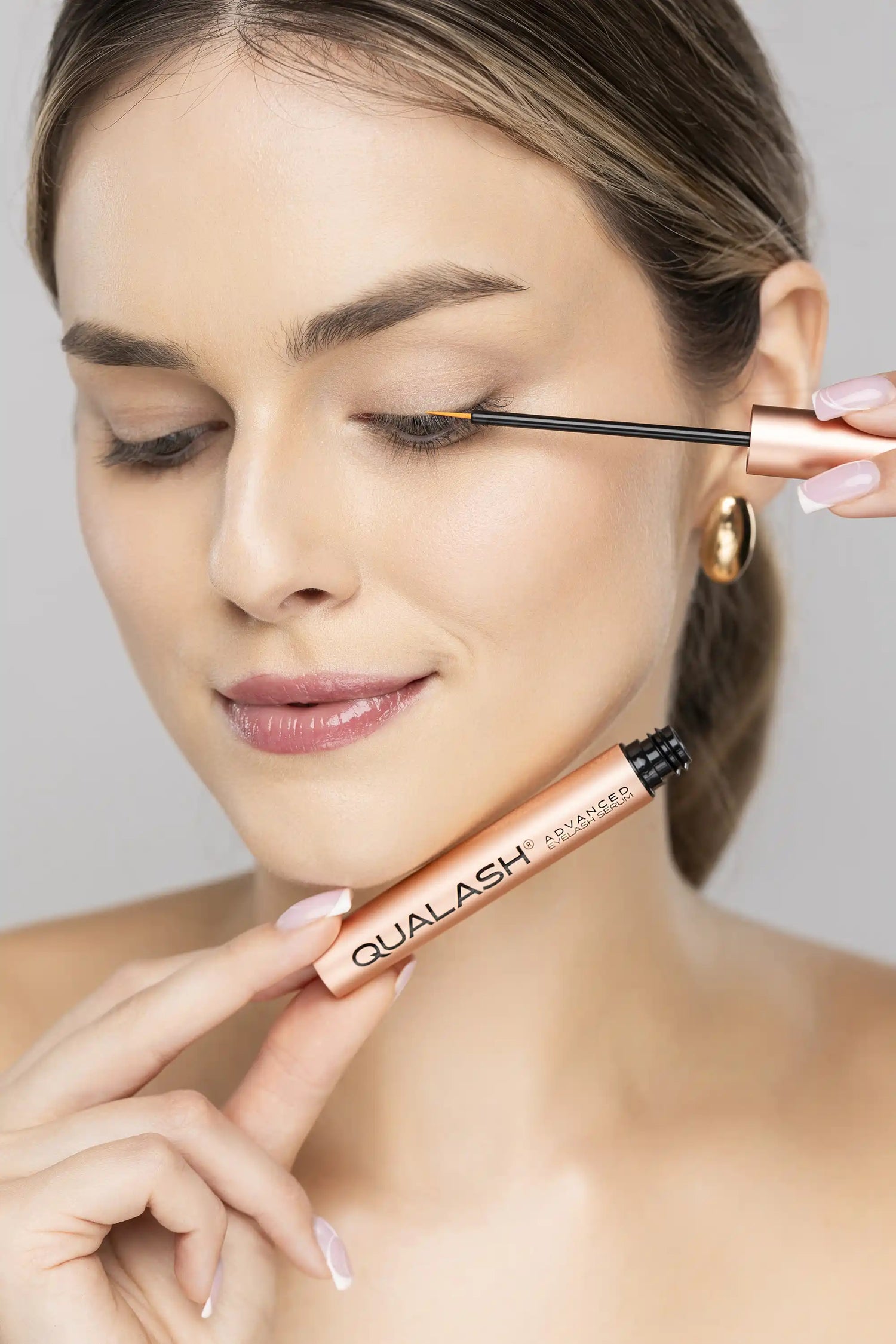 Applying QUALASH Advanced Eyelash Serum along the lash line using precision applicator